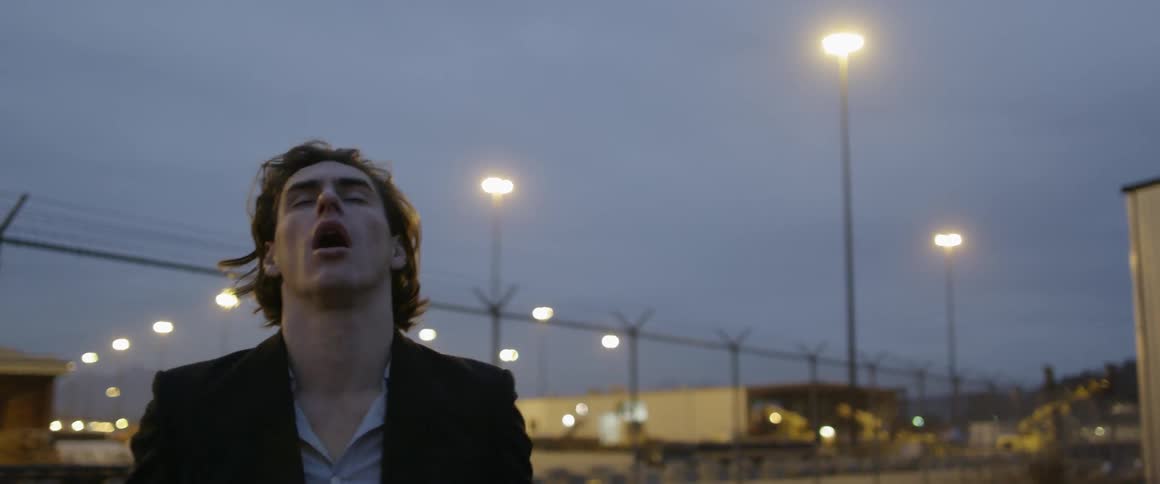 A man runs his hands over his face looking distressed as he stands outside at night