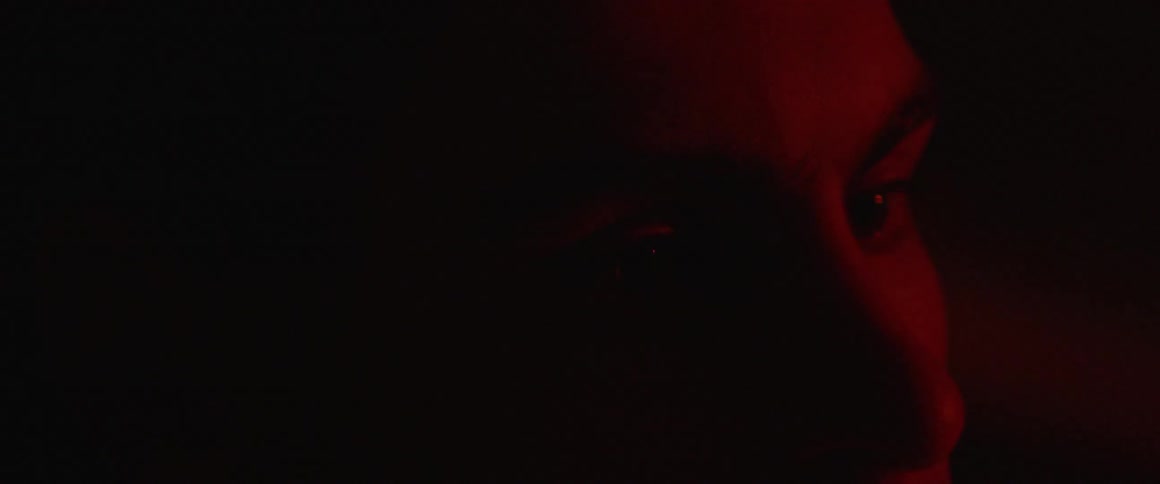 A red light glows on a man's face
