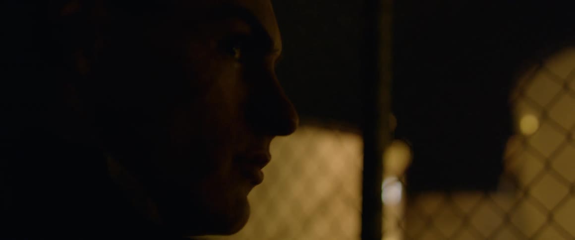 Man stands near a chain link fence inside a building