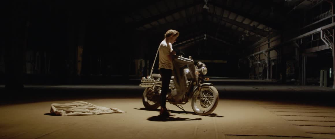 A man examines a motorcycle in a warehouse