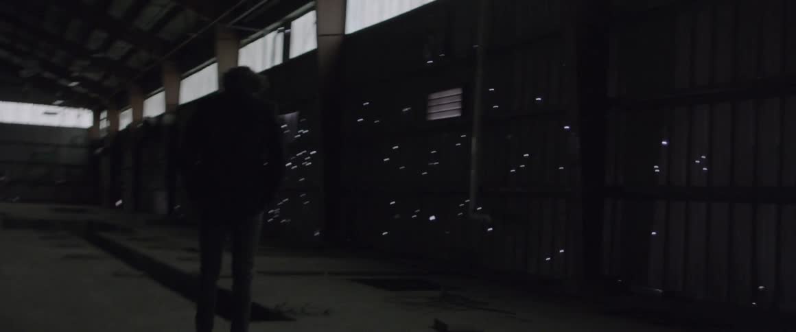 Man stands in a large building and looks at the lights on the wall