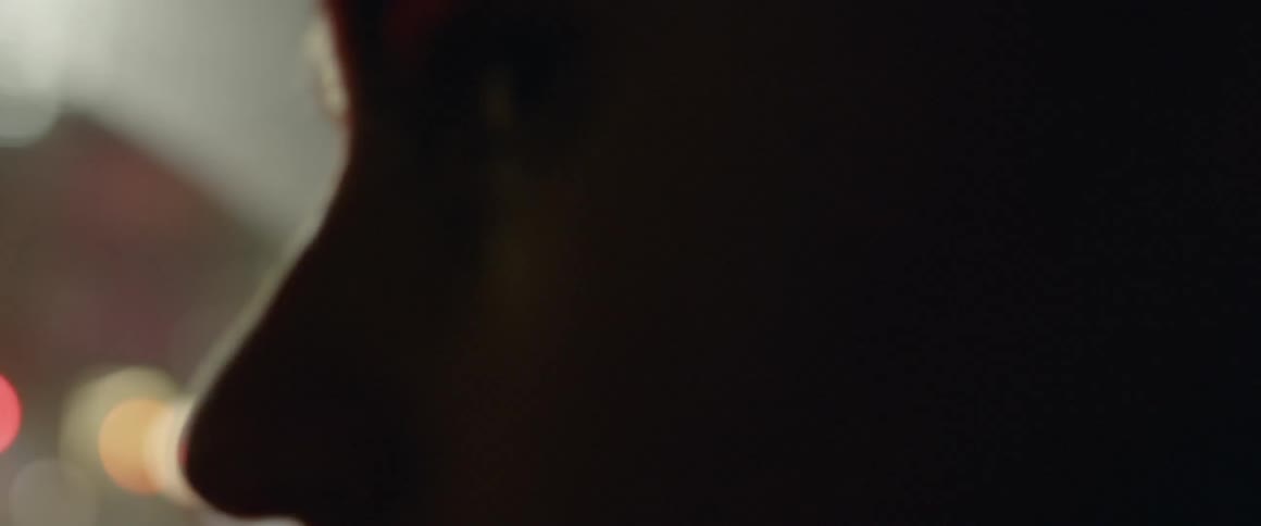 Man turns his head as he travels past the bright lights in a vehicle
