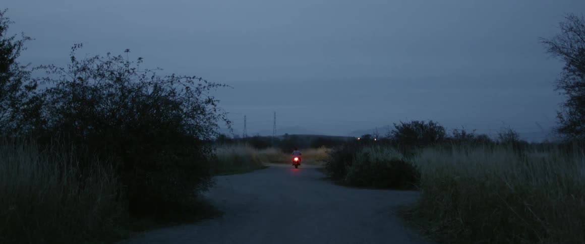 Man is riding motorcycle on cloudy evening after sunset