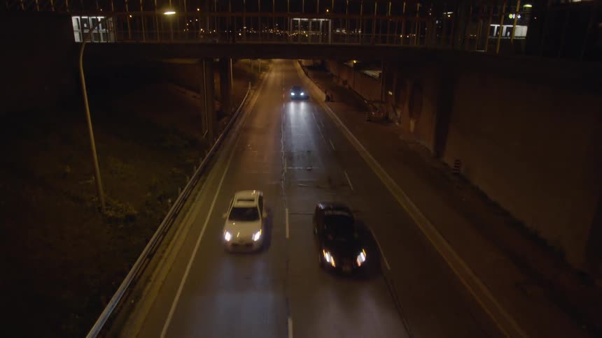 Cars travel under a bridge at night