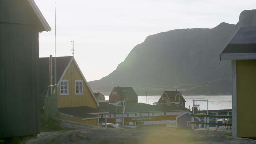 A fishing village with brightly colored buildings and cliffs in the background