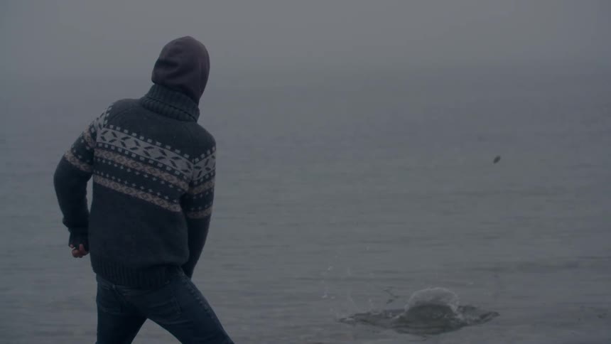 A man skips a rock on the ocean