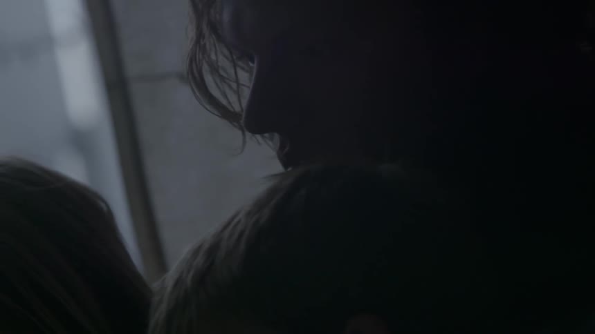 A man sits with children in a dim room