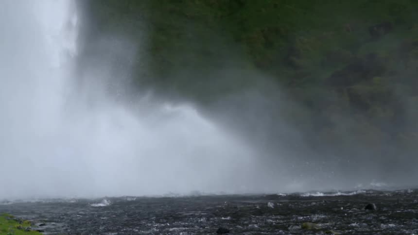 Water splashes up from a waterfall in the day