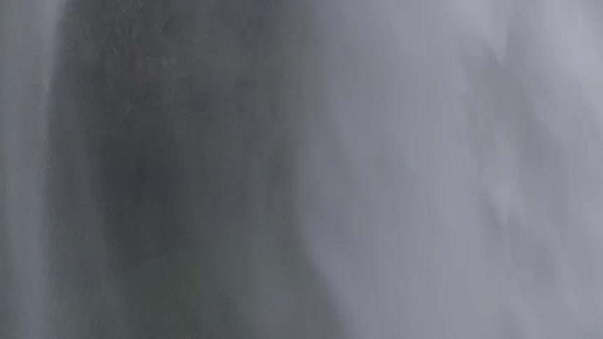 A waterfall flows near a grassy mountainside