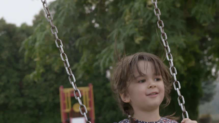 A young girl swings at a park