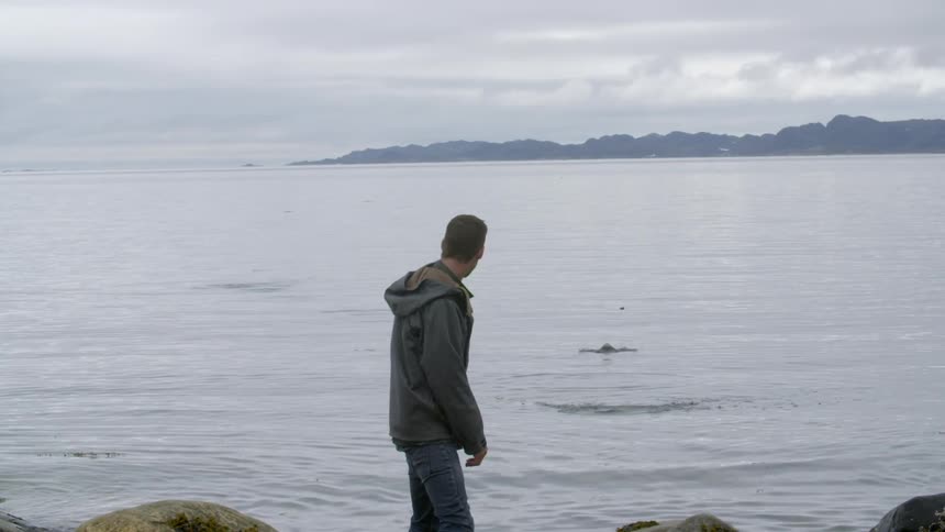 A man throws rocks into the water in slow motion