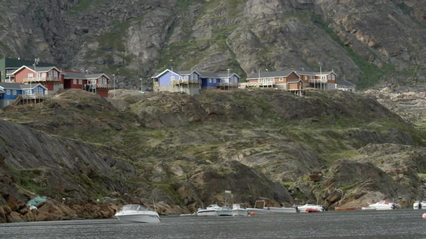 A village with brightly colored houses sitting on a hilly shoreline