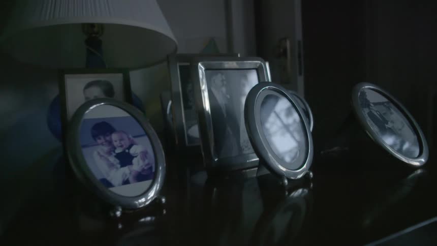 Framed photographs sit on a nightstand
