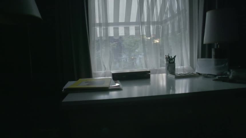 An open window near a desk in a dim room