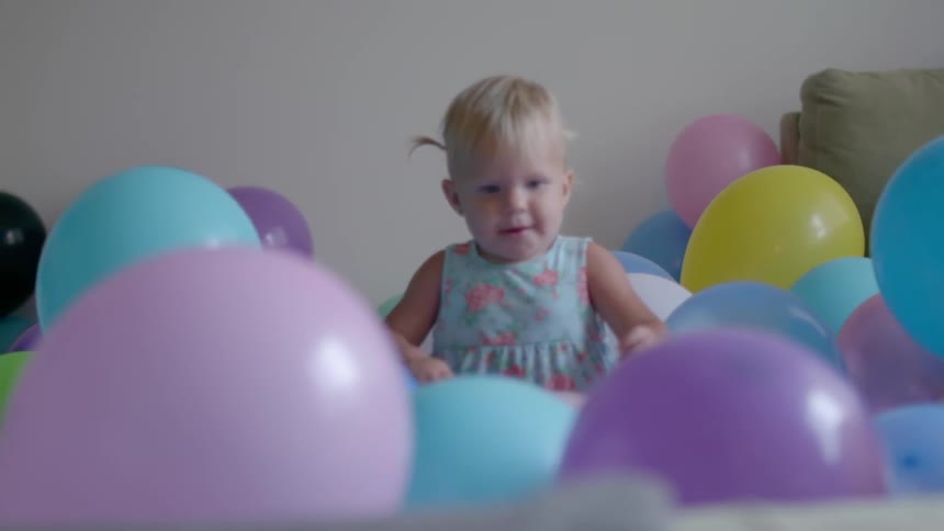 A child plays in a pile of balloons