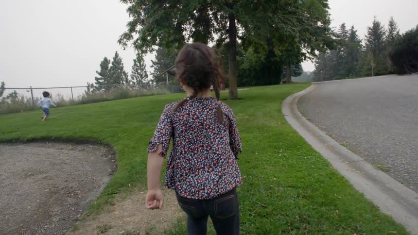 A young boy and girl running towards playground equipment