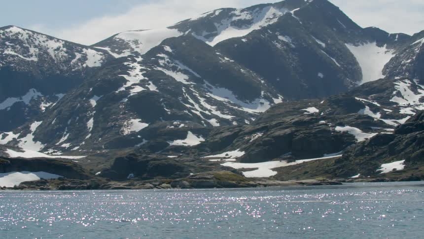 Water flows in front of snow-topped mountains