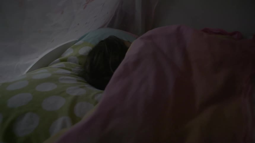 A young girls sleeps in her bed
