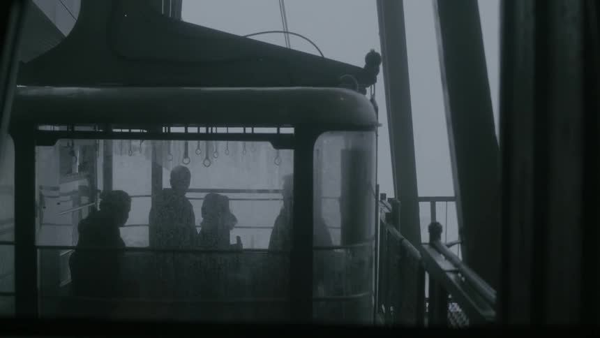 People standing inside of a gondola on a dark and cloudy day