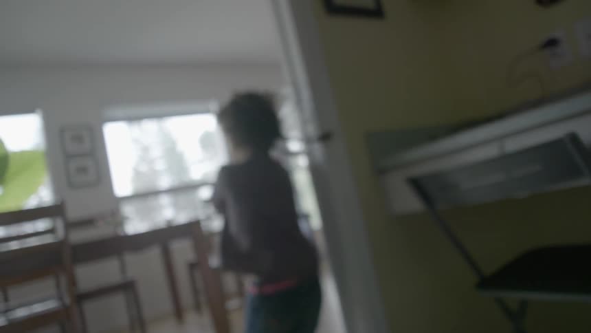 A young, brunette girl running into and through a dining area