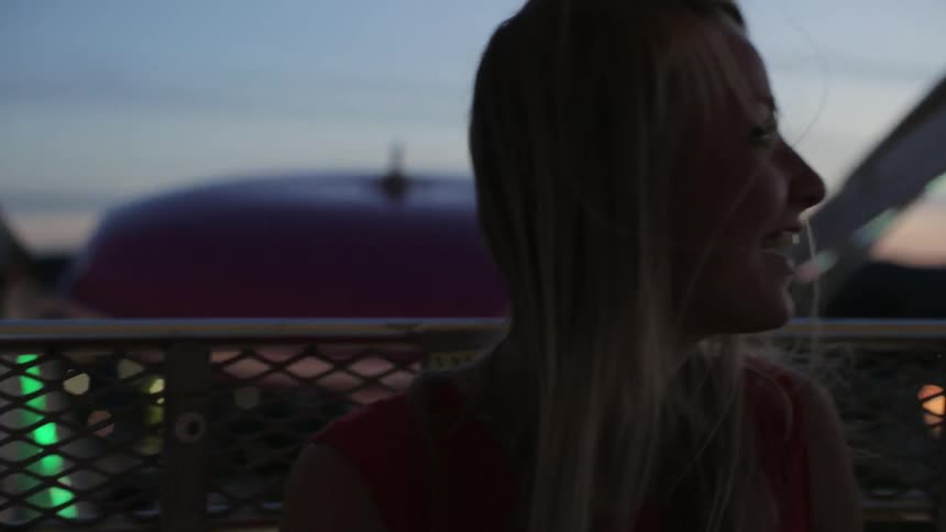 A woman rides a ferris wheel at night