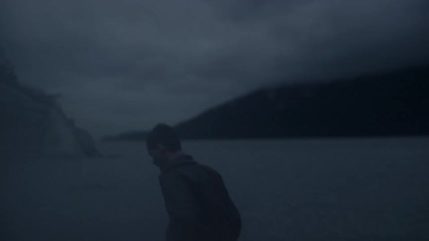 A man is silhouetted against a lake at night