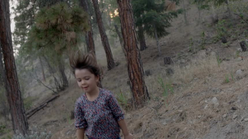 A young kid is jumping in the forest in the daytime