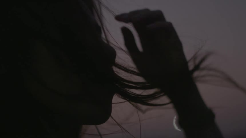 The wind blows a woman's hair around her face at night