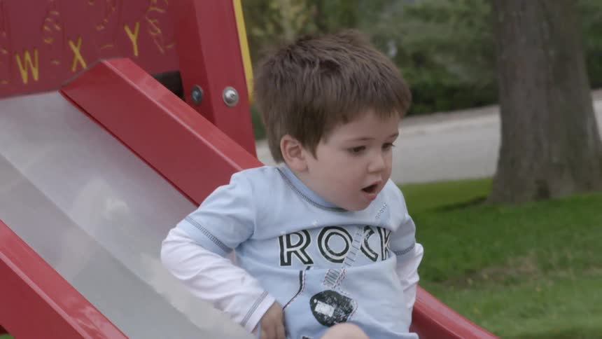 Boy is sliding down the playground slide in the park