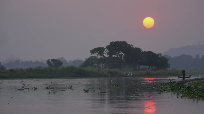 Man is moving on a boat in the lake at dawn