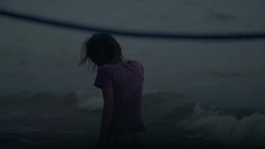 A girl stands on the beach at night