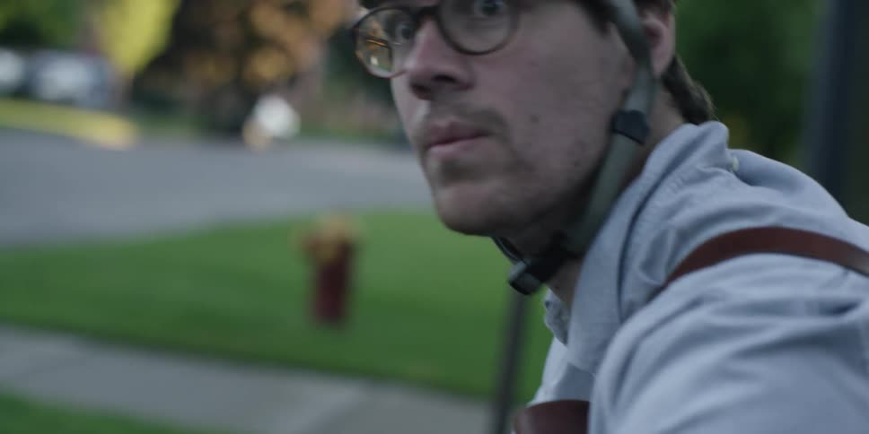 A man wearing a helmet is sitting on his bicycle and looking at his watch