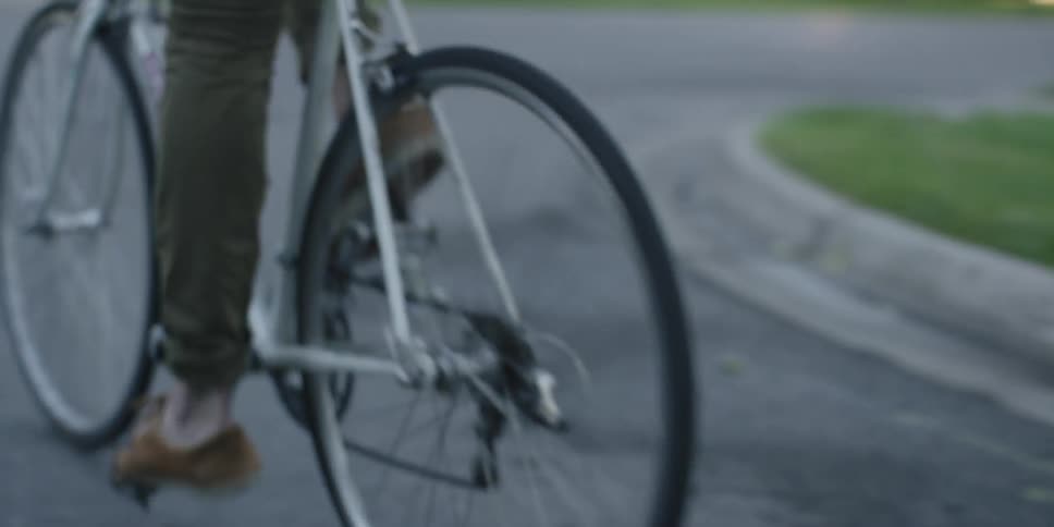 A man pushing off and pedaling a bicycle down a street