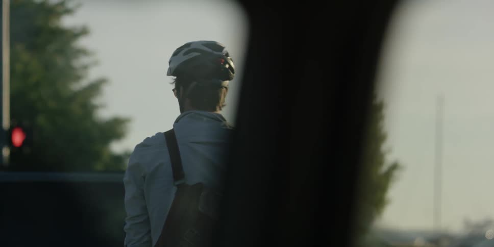 Cars drive by a man in a bicycle helmet