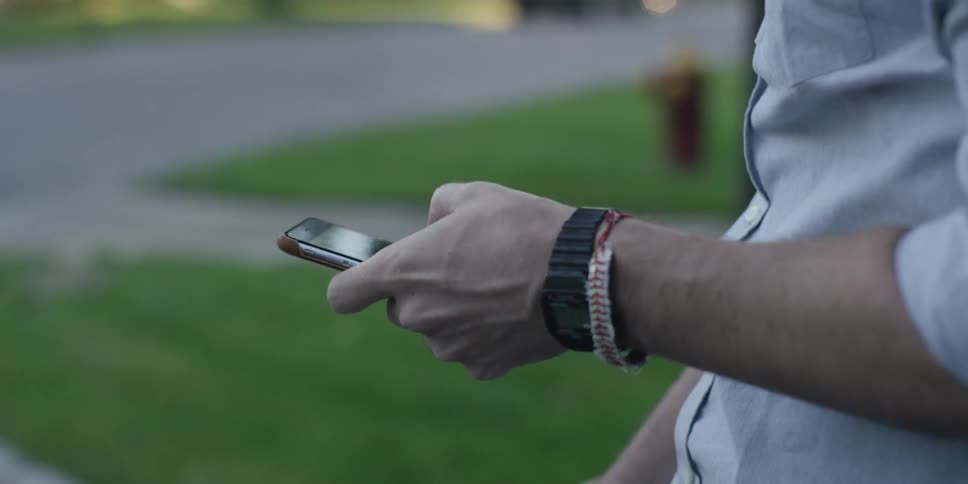 A man pulling a cell phone from his pocket as he sits on a bicycle