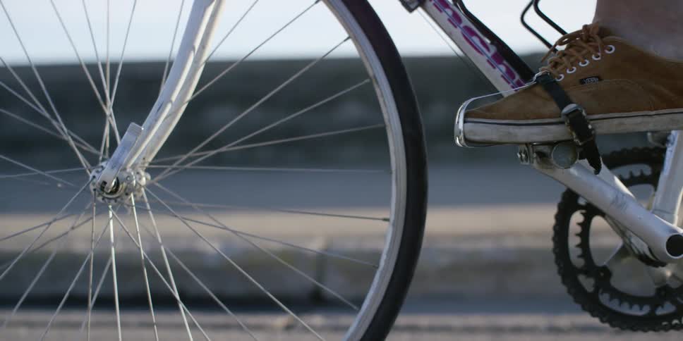 A person mounts a bicycle and starts to pedal