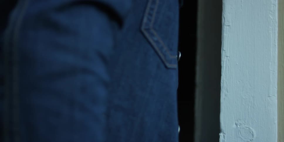 A man wearing a jean jacket opening a door