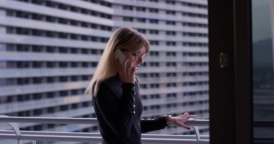 A woman uses a phone on the balcony
