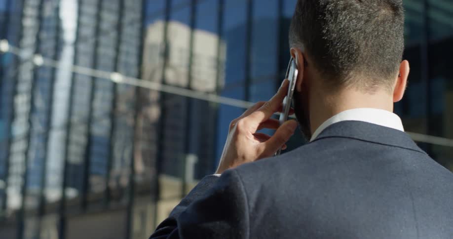 A man in a suit uses his phone outside