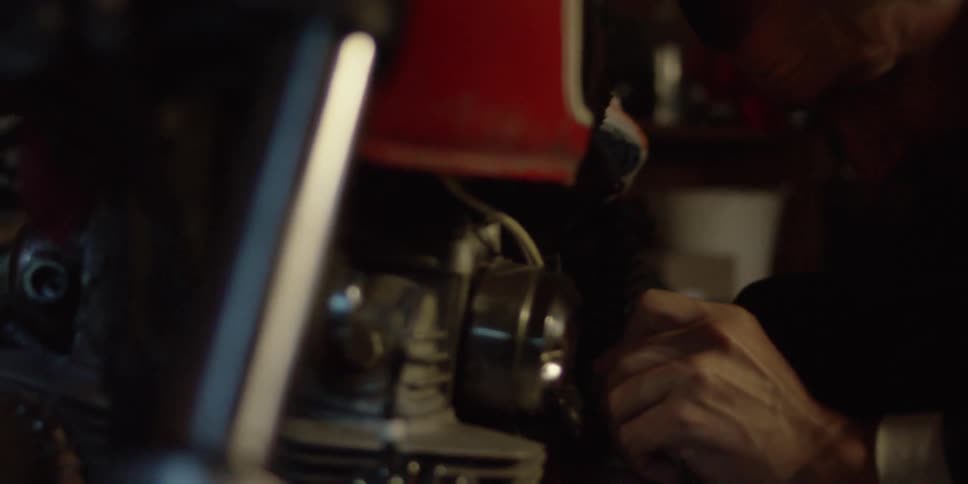 A man uses a tool on a motorcycle