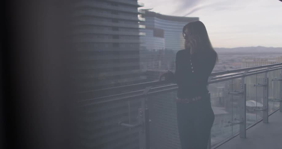 A woman uses a phone on the balcony