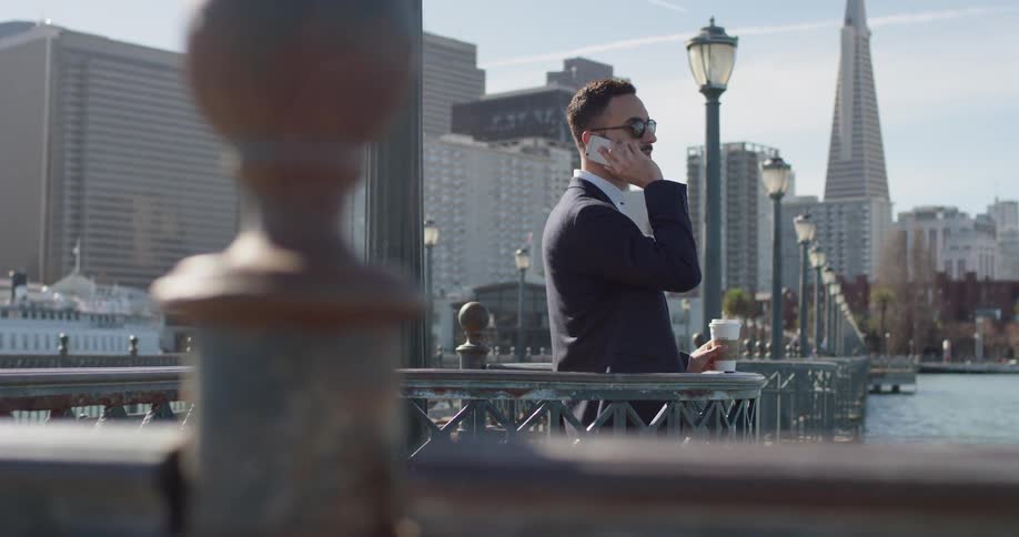 Man holds his cellphone to his ear as he stands in a city