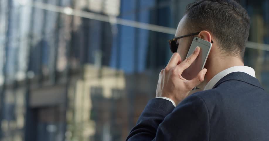 A man in a suit uses his phone outside