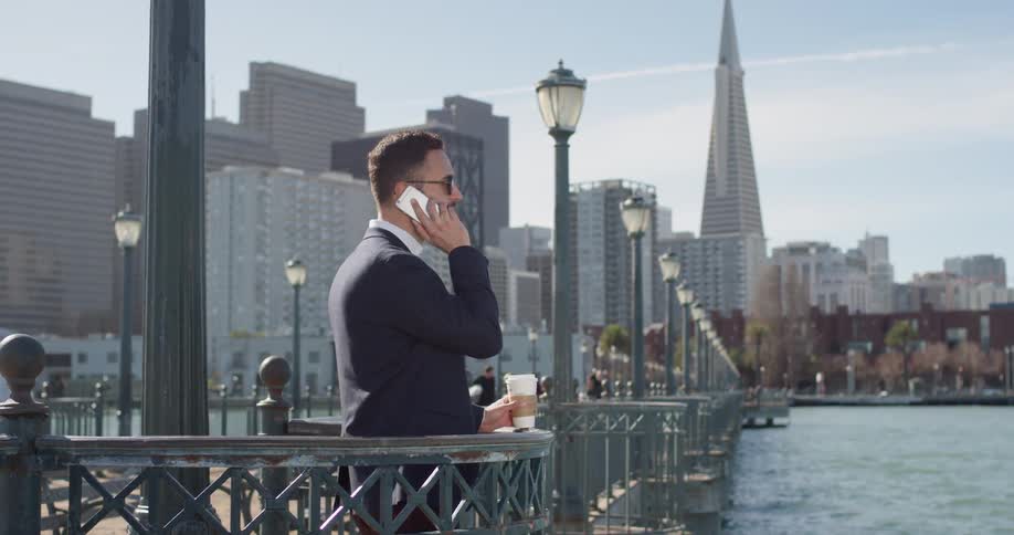 A businessman uses his phone by the water