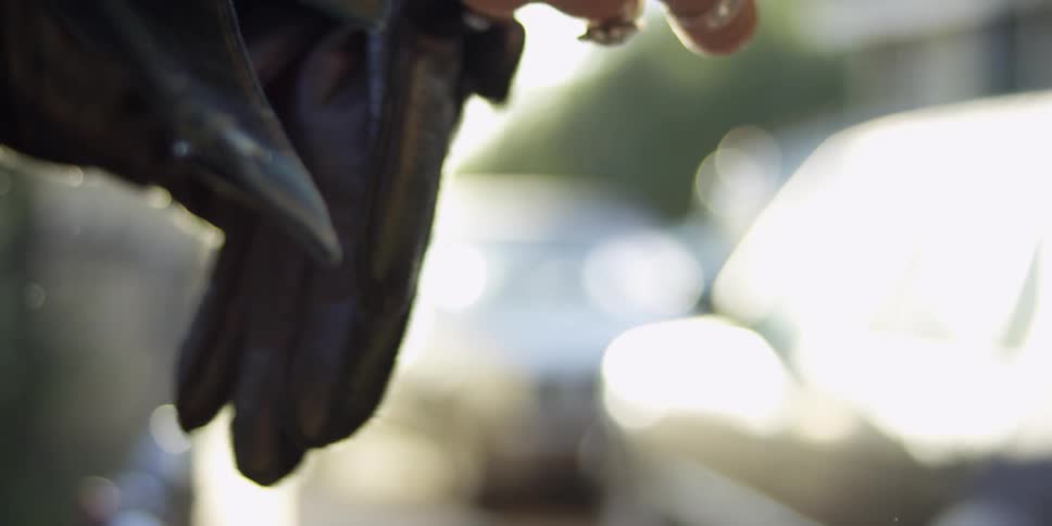 A person puts on black leather gloves