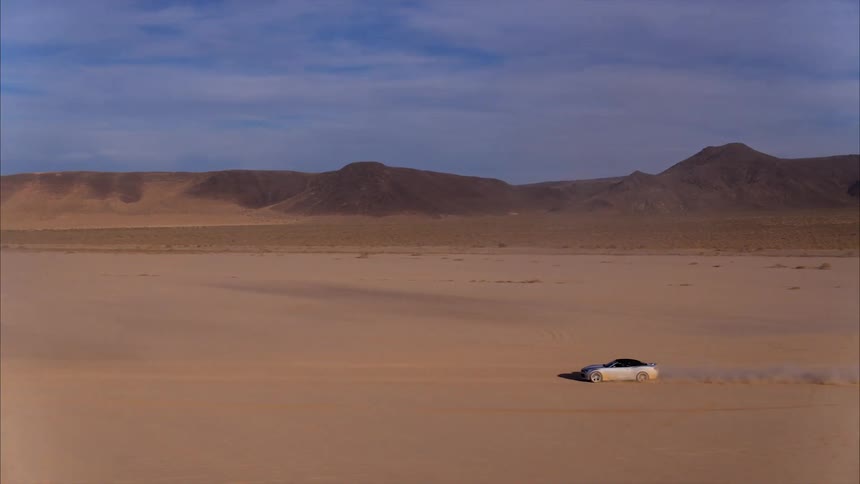 A car rides on the open desert