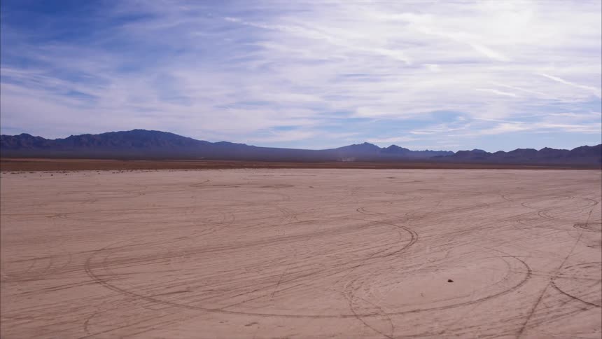 The sandy field sits near the hills under the cloudy blue sky