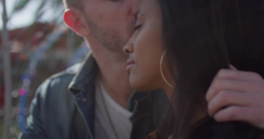 A man kisses a woman's forehead outside