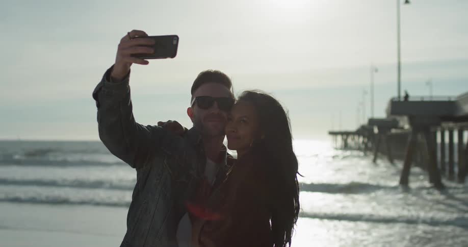 A man and woman take a selfie on the beach