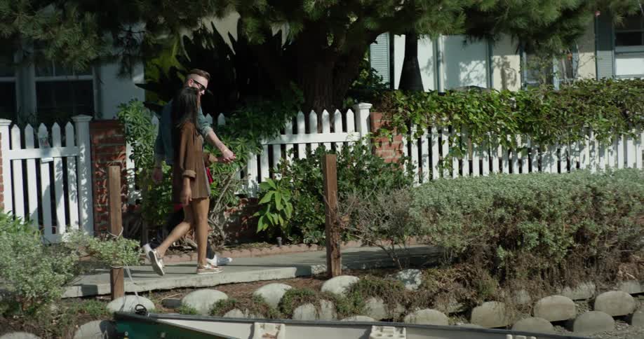 A man and woman hold hands as they walk by houses